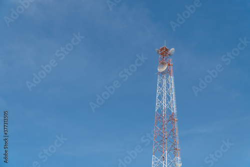 Telecommunication tower with blue sky and cloud in background. Broadcast pole with copy space. Wireless communication technology.