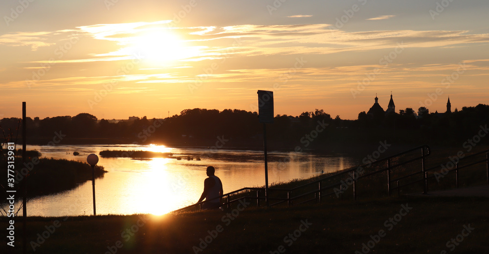 Beautiful sunset landscape on the river. Vacation and travel concept. Silhouette of a man on a background of water.