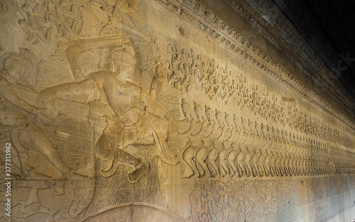 Ancient Khmer bas relief carving showing a row of Devas, angels, pulling on the snake Vasuki. Legend of the churning of the Ocean of Milk, Angkor Wat temple, Cambodia. photo