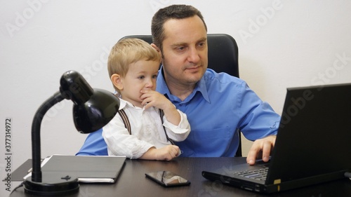 Man working at laptop in office, child tasting at computer, worried babysitter