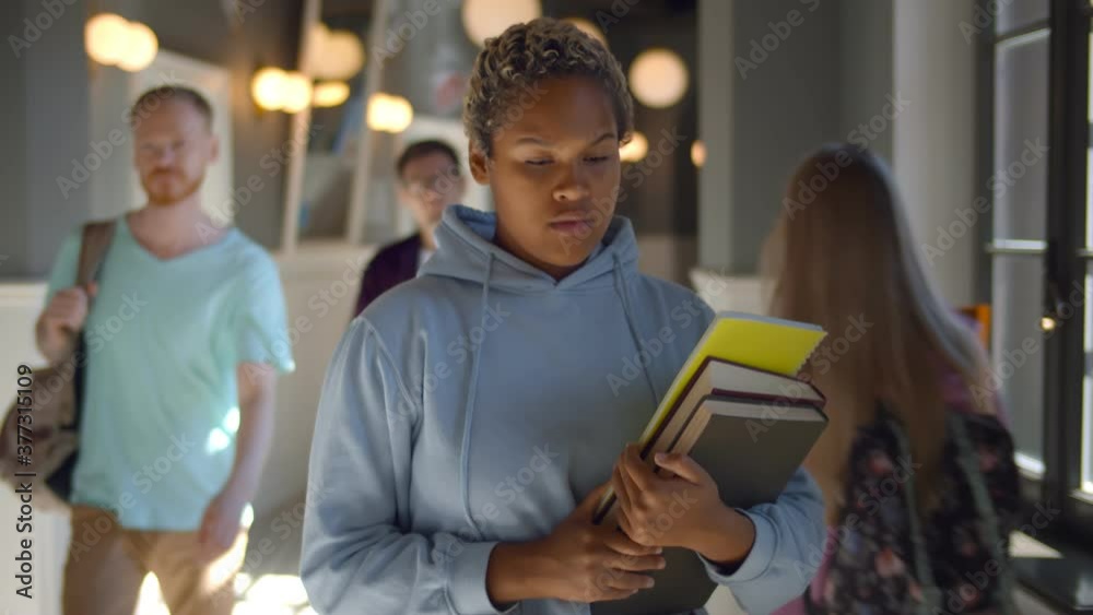 Portrait of sad african female student walking through university corridor