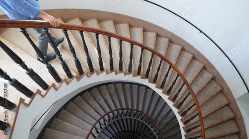 Slika na platnu Man going down the interior spiral stairs of luxury modern building