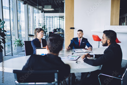 Colleagues sitting at round table in modern conference room during meeting