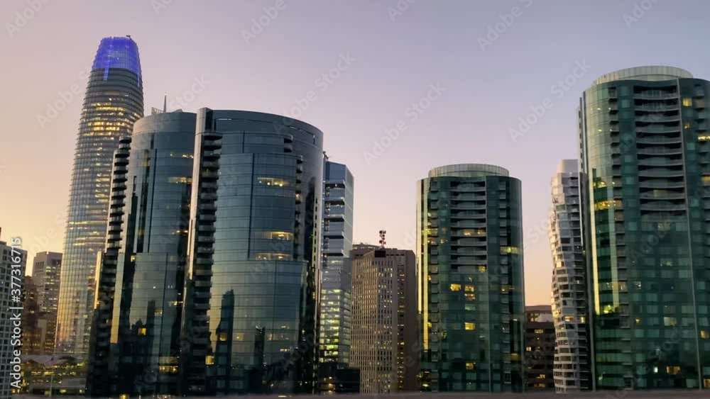 Downtown office buildings view in motion at sunset from afar, highway - ground level. San Francisco, California.