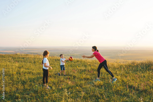 mother and children playing with ball on meadow