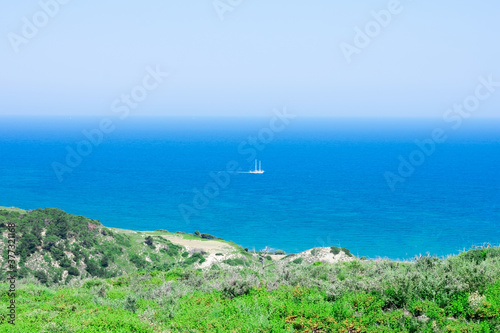 Beautiful seascape with calm blue Mediterranian sea, mountains in mist and boat, touristic season, vacation on sunny islands