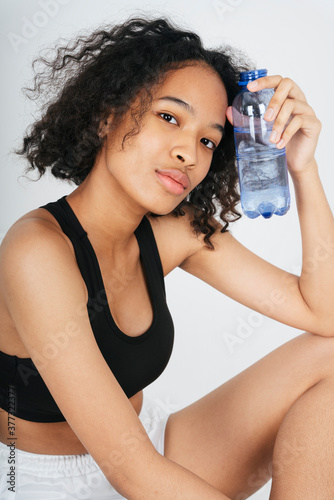 Mixed race african and thai woman holding a bottle of water.