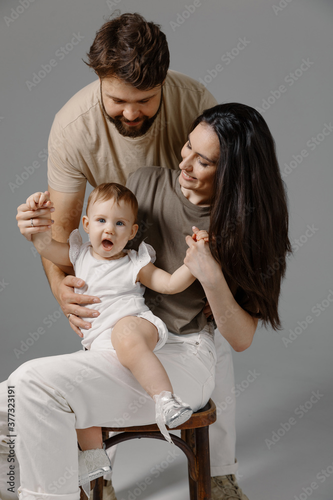 Photo of the happy young family with little child staying on the floor - isolated on white background studio. Lifestyle, happiness, love