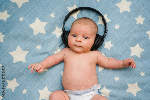 Obraz na płótnie Bebe escuchando musica con cascos inalambricos sobre la cama con estrellas w salonie