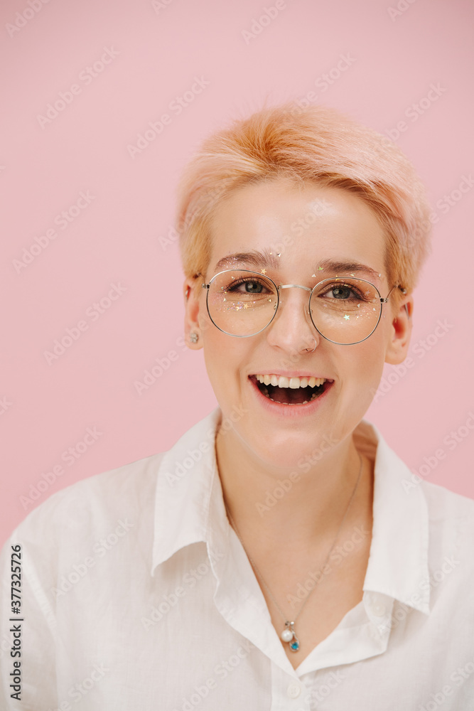 Happy young woman with short blond hair, round glasses and stars eye makeup Happy young woman with short blond hair, round glasses and stars eye makeup