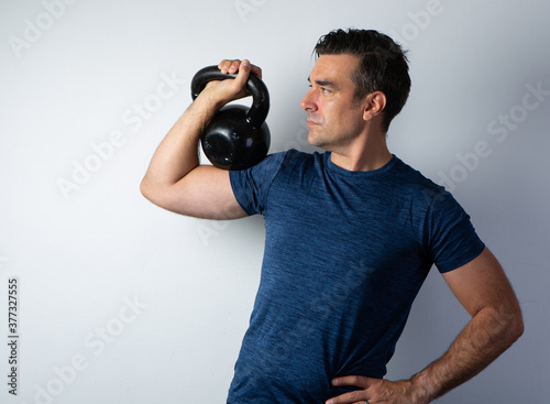 Strong dark man lifting kettlebell