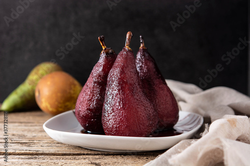 Poached pears in red wine on wooden table. 