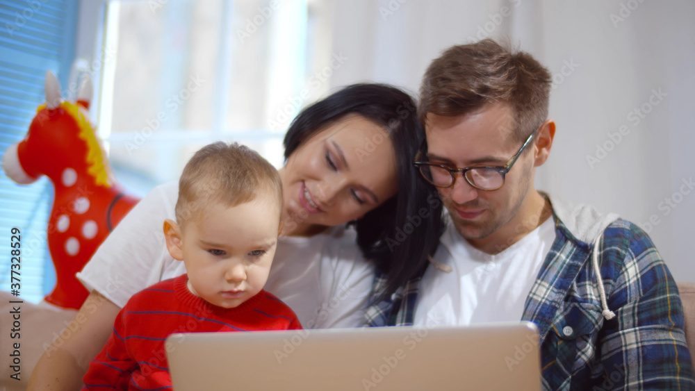 Young parents watching cartoons on laptop with cute baby boy Young parents watching cartoons on laptop with cute baby boy