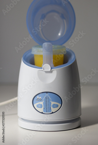 Digital baby food and bottle warmer with open lid and storage container in it on the white background