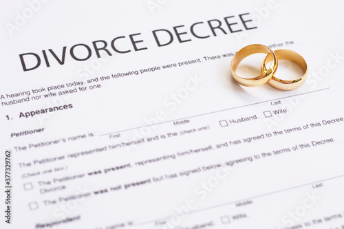 Two broken golden wedding rings divorce decree document. Divorce and separation concept 