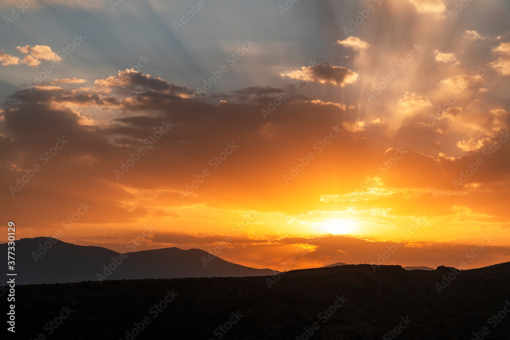 Obraz premium Beautiful bright sunset sky over the mountains silhouette . Dramatic orange clouds after sunset. Nature backgrounds. Golden sunset.