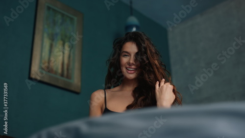 Sexy girl biting lip in modern bedroom. Long hair woman posing in bed.