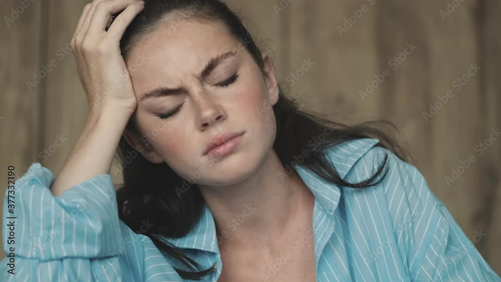 A displeased woman is touching her temples while working with paper documents while sitting at home A displeased woman is touching her temples while working with paper documents while sitting at home