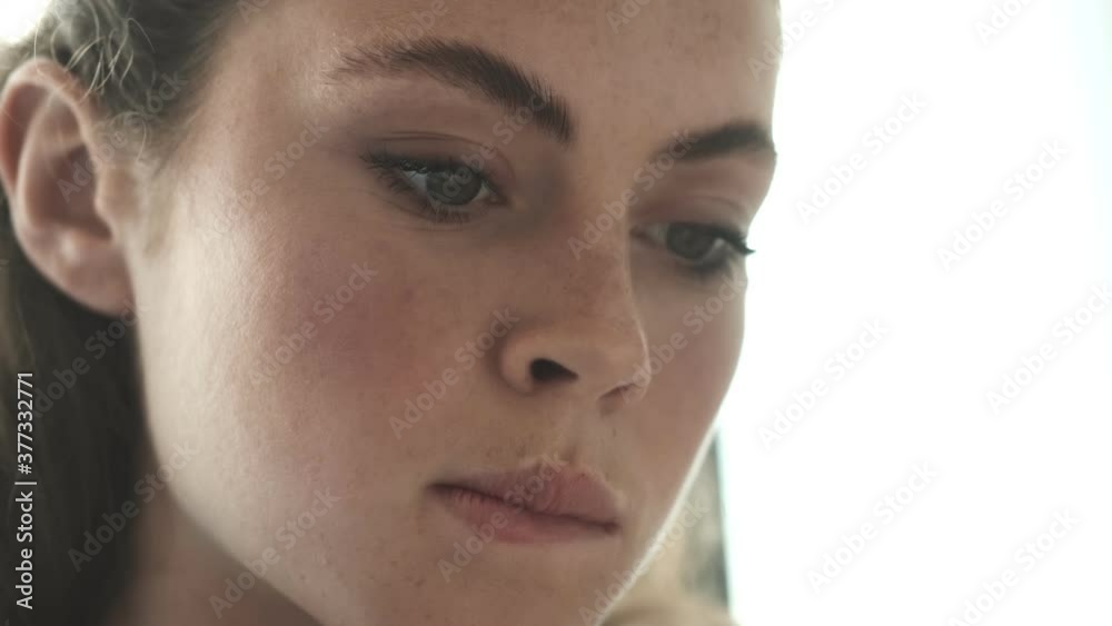 A close-up view of a concentrated young woman is reading a book sitting in the living-room at home A close-up view of a concentrated young woman is reading a book sitting in the living-room at home