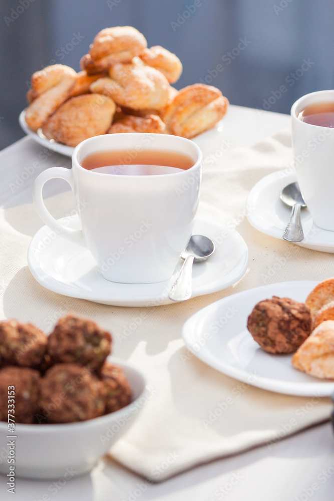 Fresh homemade sugar cookies with tea on white table with sun lights. Good morning or day concept. Fresh homemade sugar cookies with tea on white table with sun lights. Good morning or day concept.