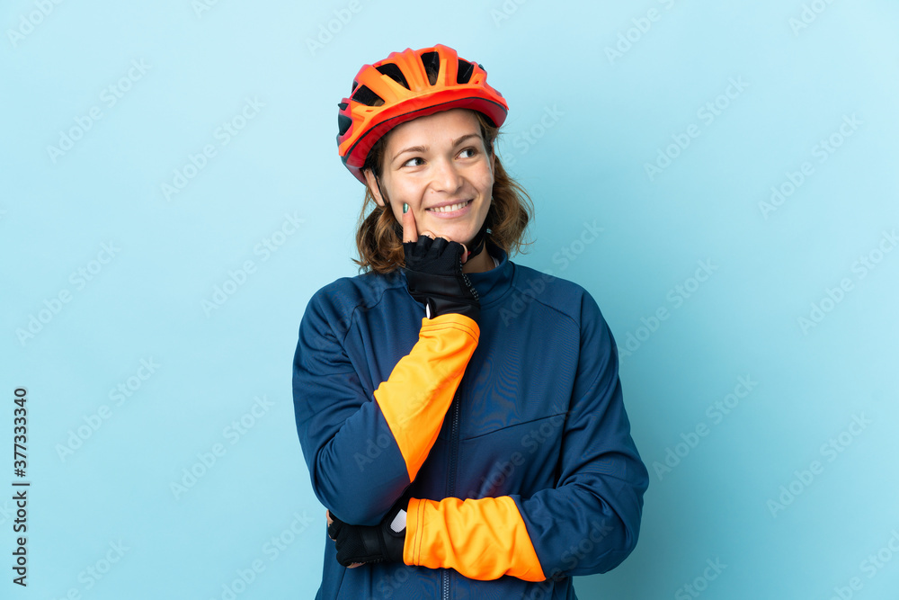 Young cyclist woman isolated on blue background thinking an idea while looking up Young cyclist woman isolated on blue background thinking an idea while looking up