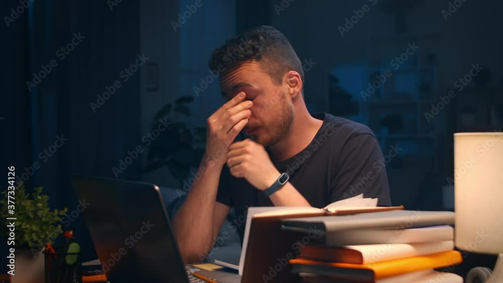Very tired young man working late at home