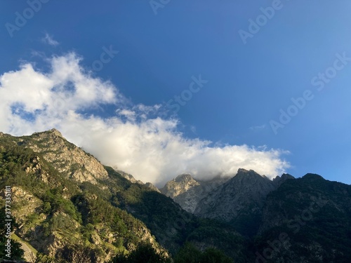 Mountain peaks against cloudy sky. Peaks of magnificent rocks located against bright cloudy sky on sunny day in nature.