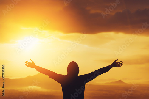 Copy space of man rise hand up on top of mountain and sunset sky abstract background.