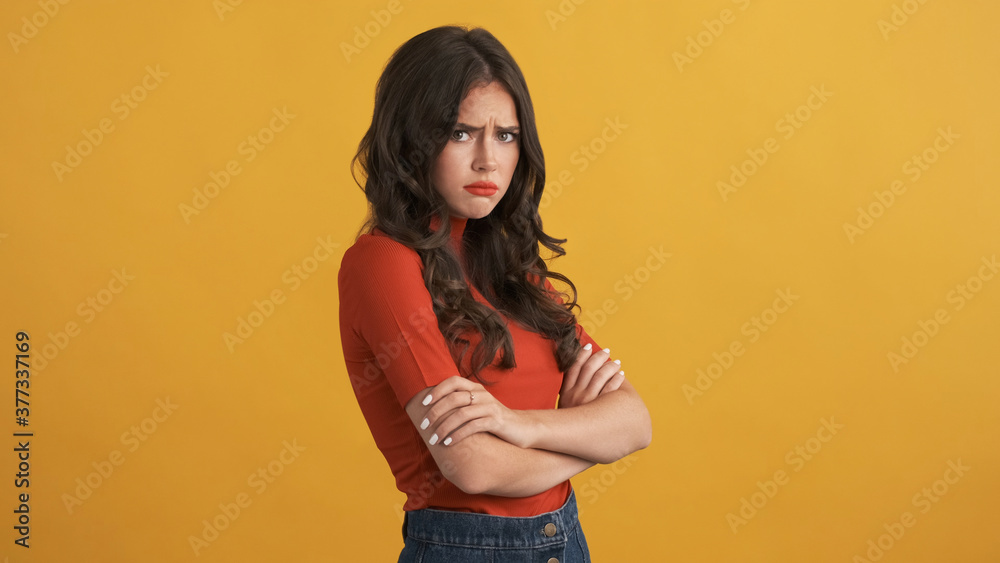 Offended girl in red top with hands crossed sadly looking in camera isolated Offended girl in red top with hands crossed sadly looking in camera isolated