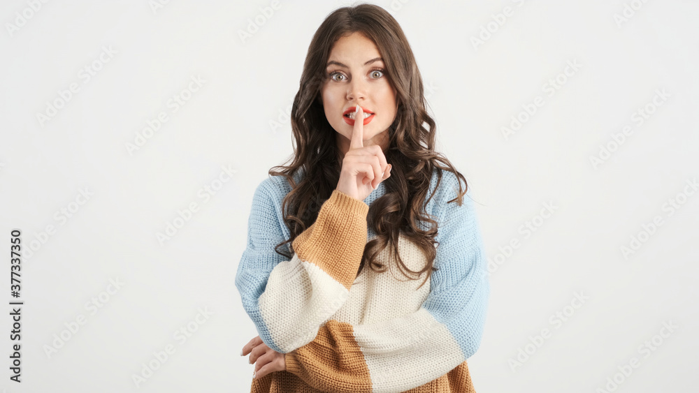 Attractive girl amazedly showing silence gesture on camera over white background. Keep secret expression Attractive girl amazedly showing silence gesture on camera over white background. Keep secret expression