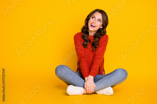 Full body photo of candid excited girl sit floor legs crossed look copyspace enjoy rejoice ads sales wear denim sweater isolated over shine color background
