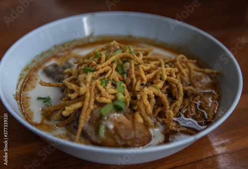Traditional Khao Soi Recipe, Thai Northern Style Curried Noodle Soup with Chicken in white bowl. Selective focus.