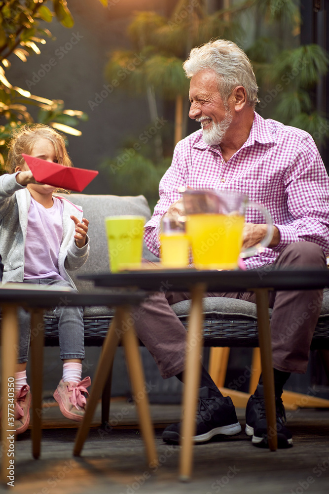 Φωτογραφία grandfather enjoying with his granddaughter sitting outdoor on a soda, smiling,