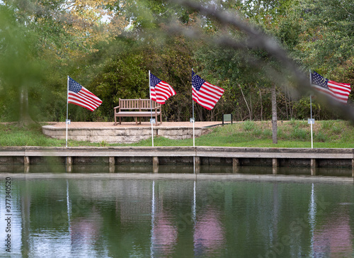 Obraz na plátně American Flags reflecting off the water of a pond in a public park in Montgomery, TX