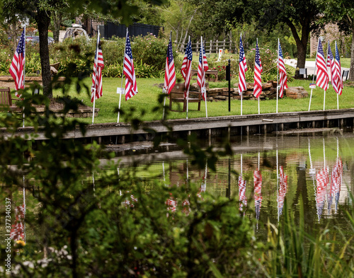American Flags reflecting off the water of a pond in a public park in Montgomery, TX. photo