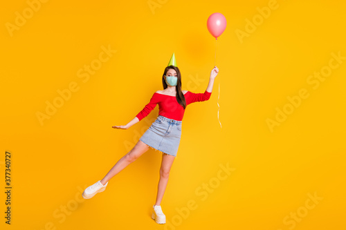 Full length photo of beautiful girl in medical mask catch air fly wind balloon wear red top casual denim jeans skirt legs isolated over bright shine color background