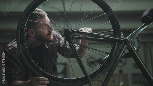 The cyclist repairs the bike in a garage, turns the wheel photo