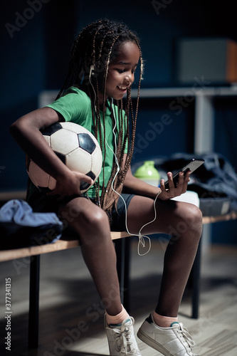 A little soccer player enjoying content on cell phone in a locker room © luckybusiness