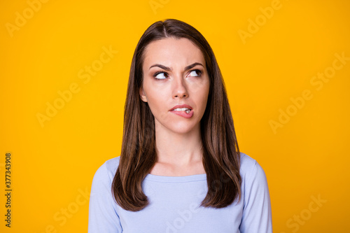 Closeup photo of attractive pretty doubtful lady look interested minded up empty space thoughtful biting lips not sure decision wear casual shirt isolated vibrant yellow color background © deagreez