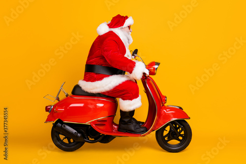 Profile side view of his he nice funny fat thick overweight white-haired Santa riding motor bike hurry rush shopping sale discount isolated bright vivid shine vibrant yellow color background