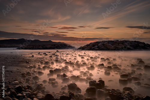 Landscape of a sunrise on the beach with rocks