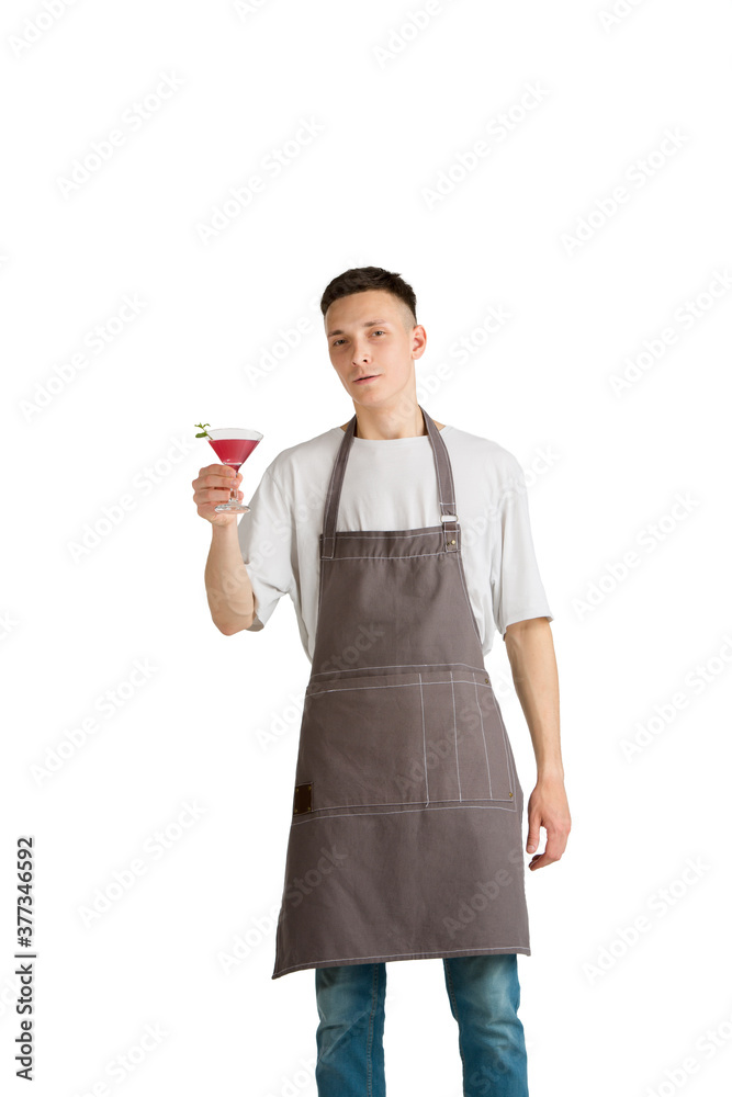 Raspberry shake. Portrait of a young male caucasian barista or bartender in brown apron. Studio white background, copyspace. Holding cocktails, inviting guests. Professional occupation, drink, service Raspberry shake. Portrait of a young male caucasian barista or bartender in brown apron. Studio white background, copyspace. Holding cocktails, inviting guests. Professional occupation, drink, service