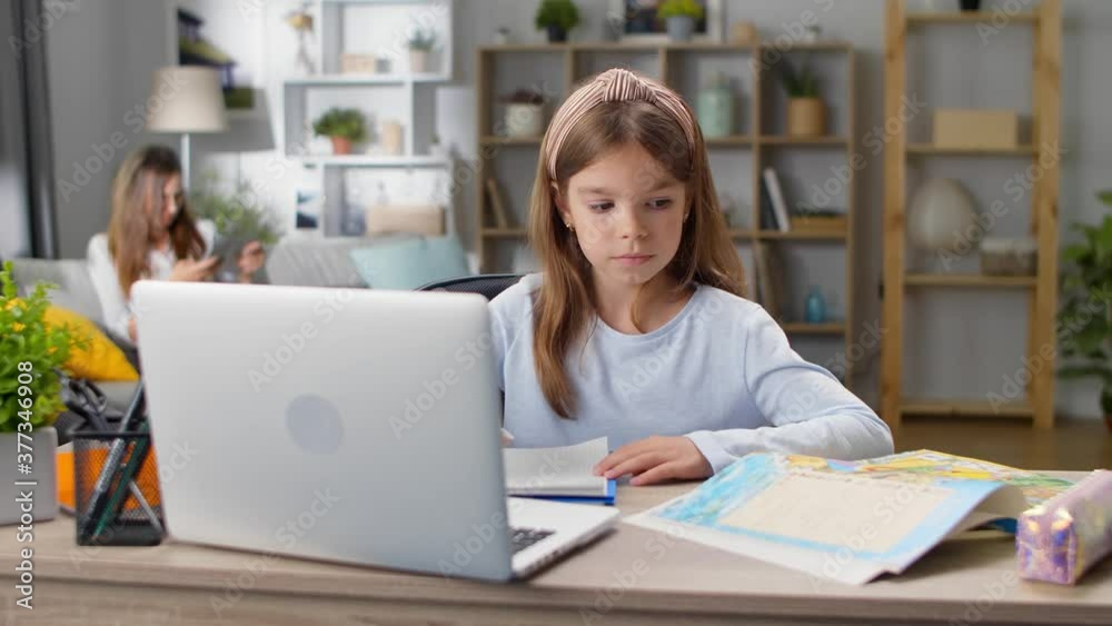 Little girl studies at home at her desk at home during quarantine Little girl studies at home at her desk at home during quarantine