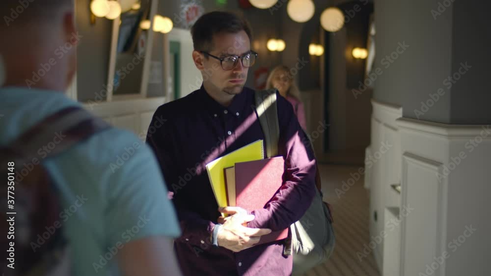 Sad male student walking looking down in university corridor Sad male student walking looking down in university corridor