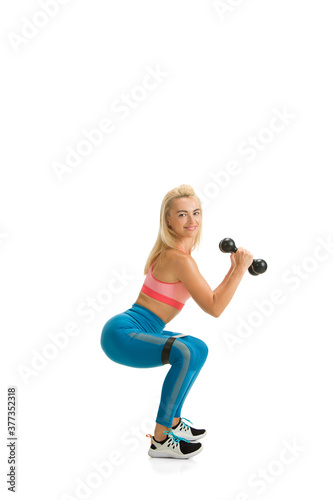 Weights. Beautiful female fitness coach practicing isolated on white studio background, showing exercises. Caucasian blonde model in sport outfit. Professional occupation, active and healthy lifestyle