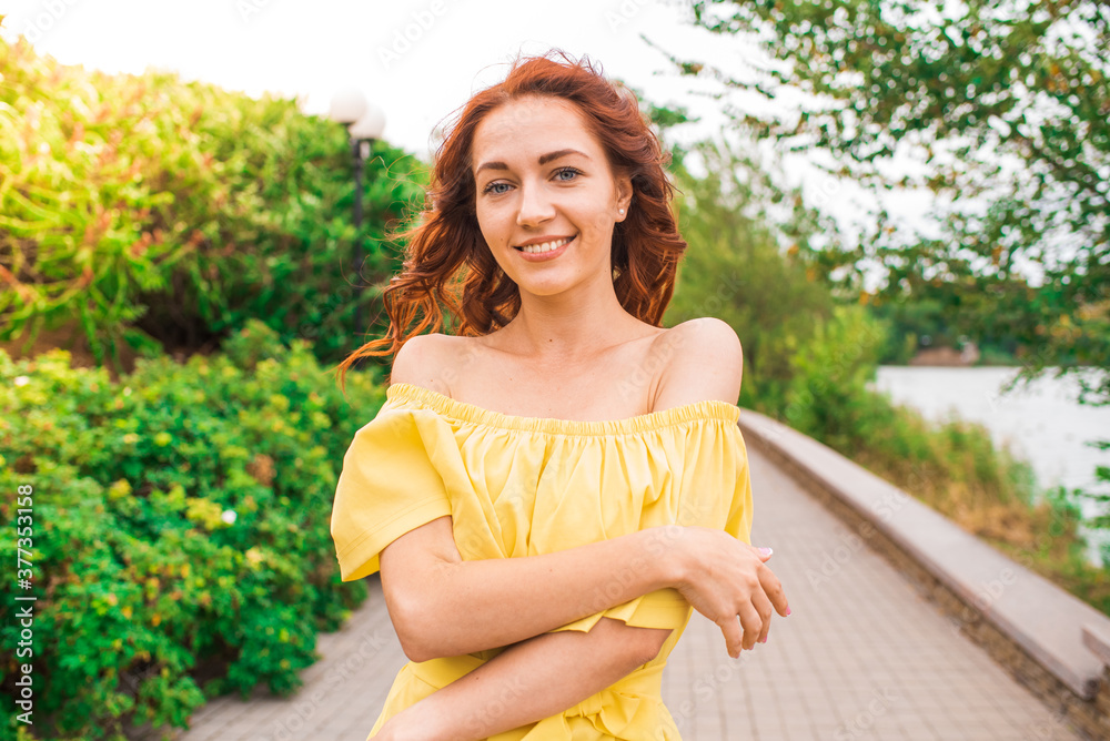 Naklejka premium Happy beautiful redhead girl walking in the park