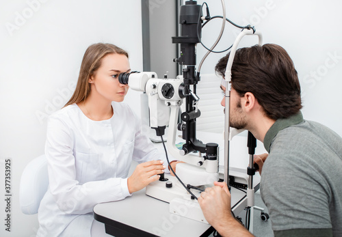 Eye doctor woman is doing a diagnostic vision exam adult man. Concept of eye care. Vision correction