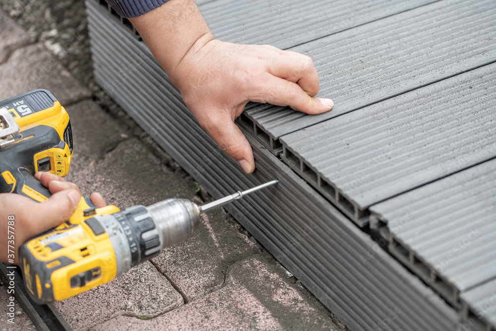 Man assembling composite deck using cordless screwdriver