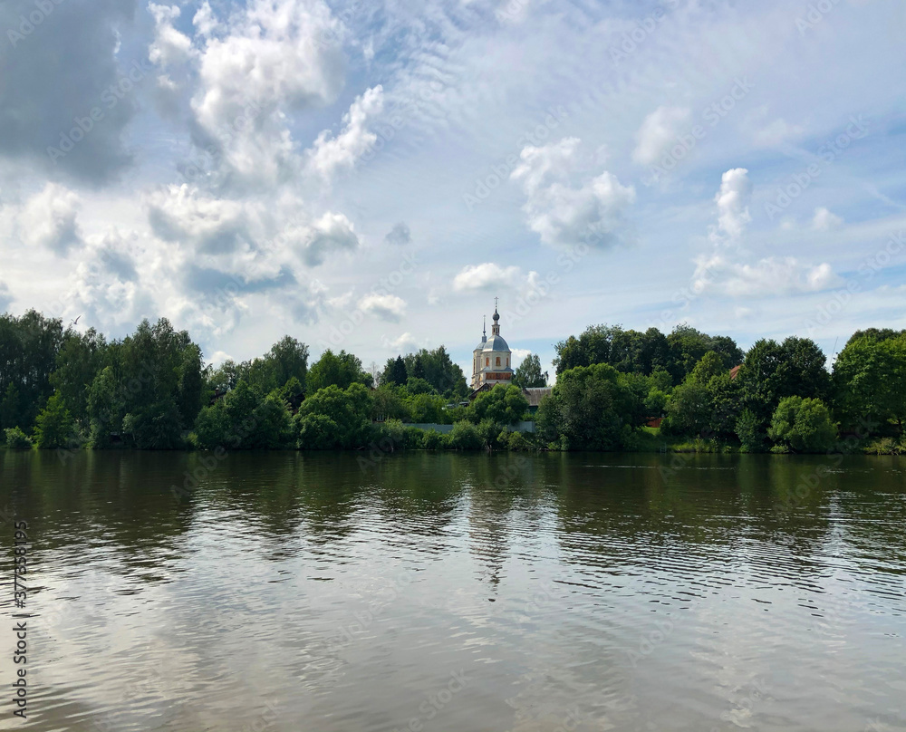 A small Church on the shore of the lake. White monastery on the background of the river Bank.