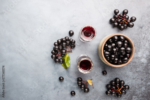 homemade black chokeberry wine or liqueur with ripe berries, top view